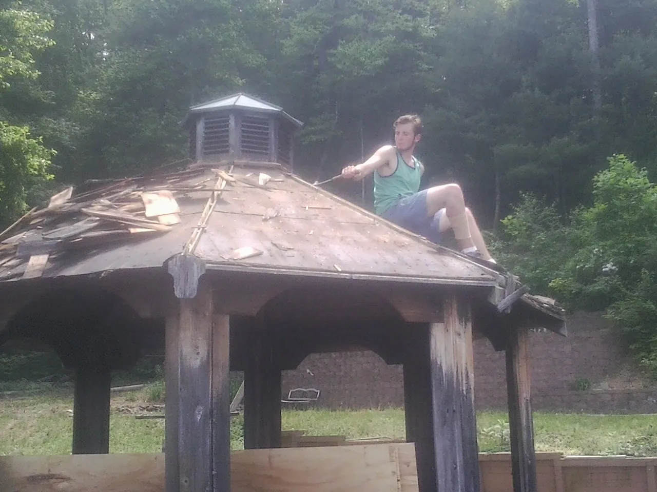 Tearing the old roof off a wooden gazebo before new shakes in Laramie