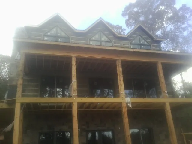 Dormers and porch framing on a large log home under construction — Roof Coating work by our crew in Laramie