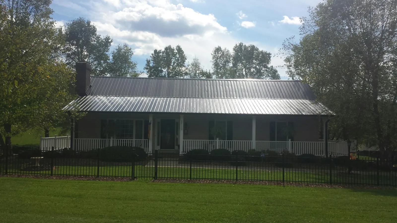 Gray metal roof on a brick ranch with a full width front porch — Gutter Guard Installation work by our crew in Laramie
