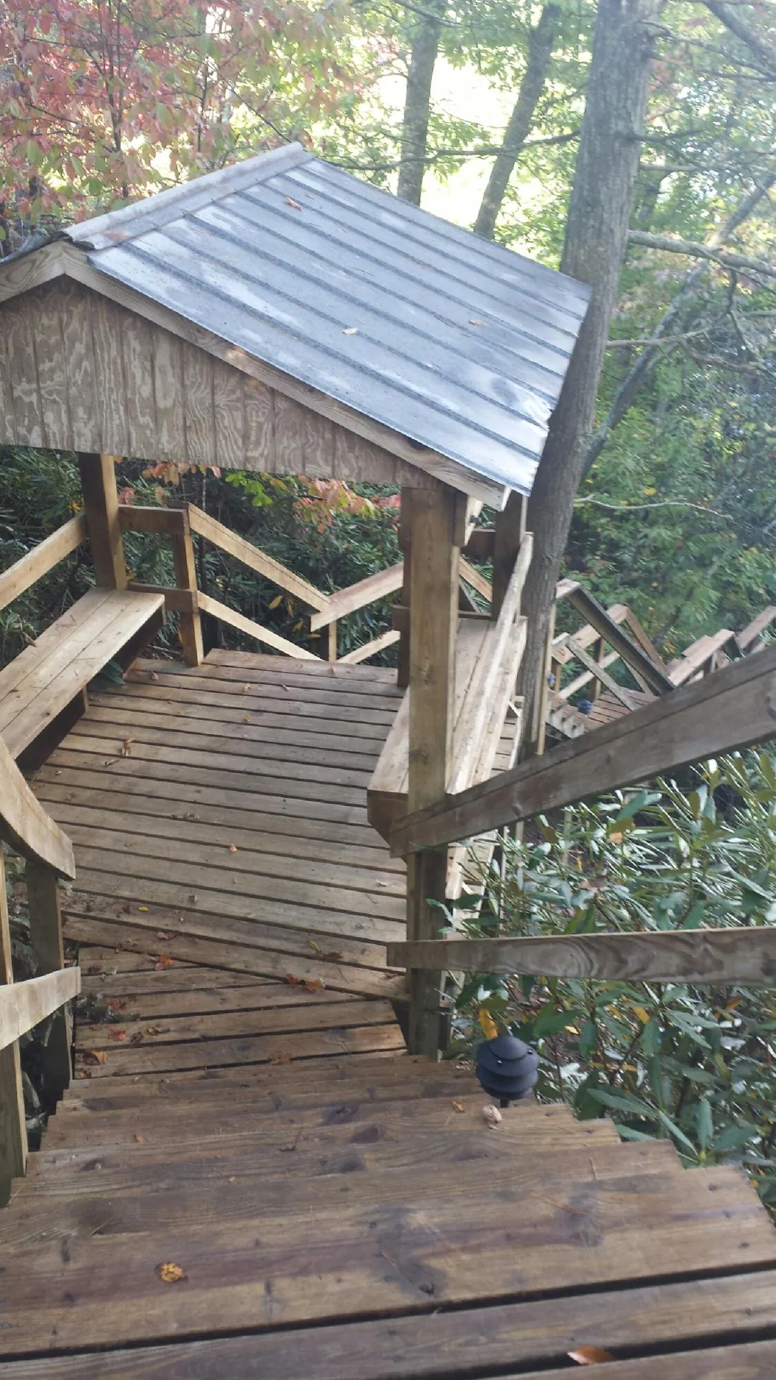 Metal roofed shelter over wooden steps on a wooded walkway — Skylight Repair & Installation work by our crew in Laramie