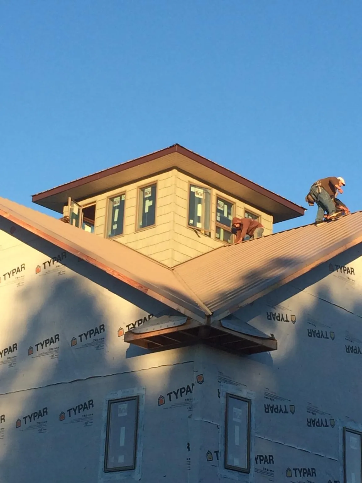 Roofers working around a rooftop cupola on a new metal roof at sunset — Roof Waterproofing in Laramie by Roofing Brothers